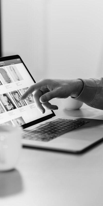 Black and white photo of a person shopping online on a laptop, highlighting e-commerce technology.