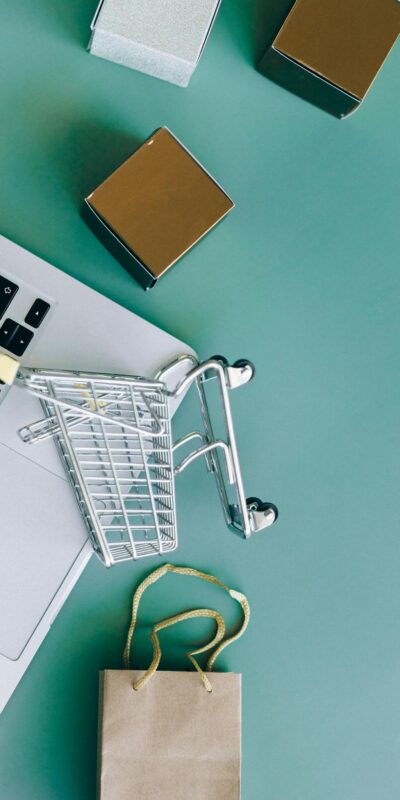 Flat lay of a laptop, shopping cart, and parcels symbolizing online shopping and ecommerce.